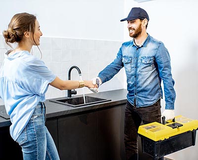 Plumber shaking hands with a homeowner in a kitchen